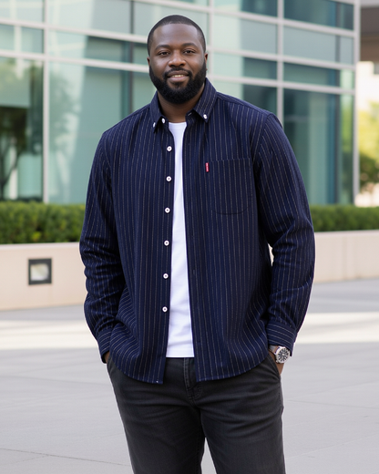 Man wearing a navy pinstripe long sleeve shirt with a red label in front of a modern building.